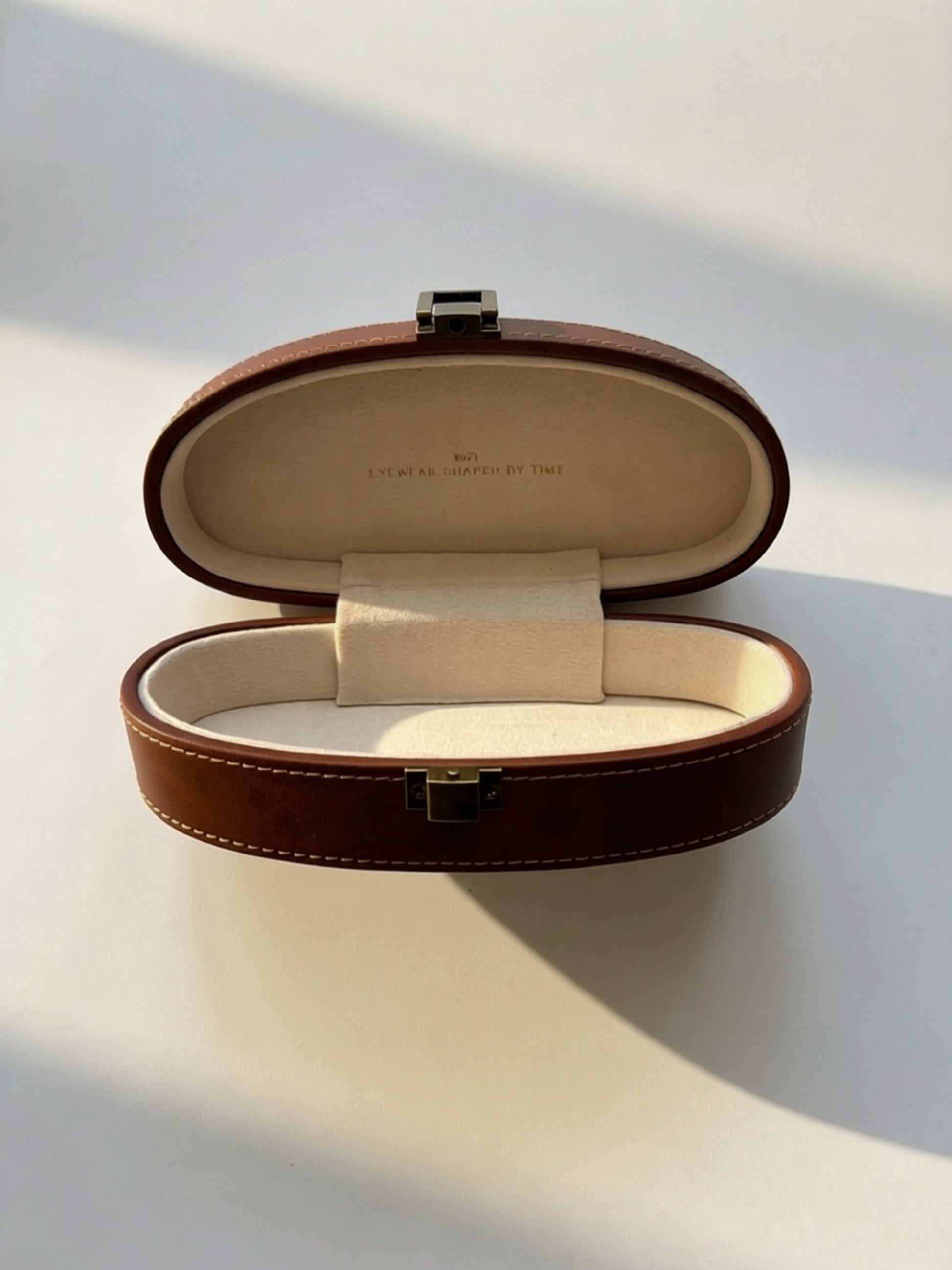 Open premium brown leather eyewear case with soft cream interior designed for luxury sunglasses and optical frames.