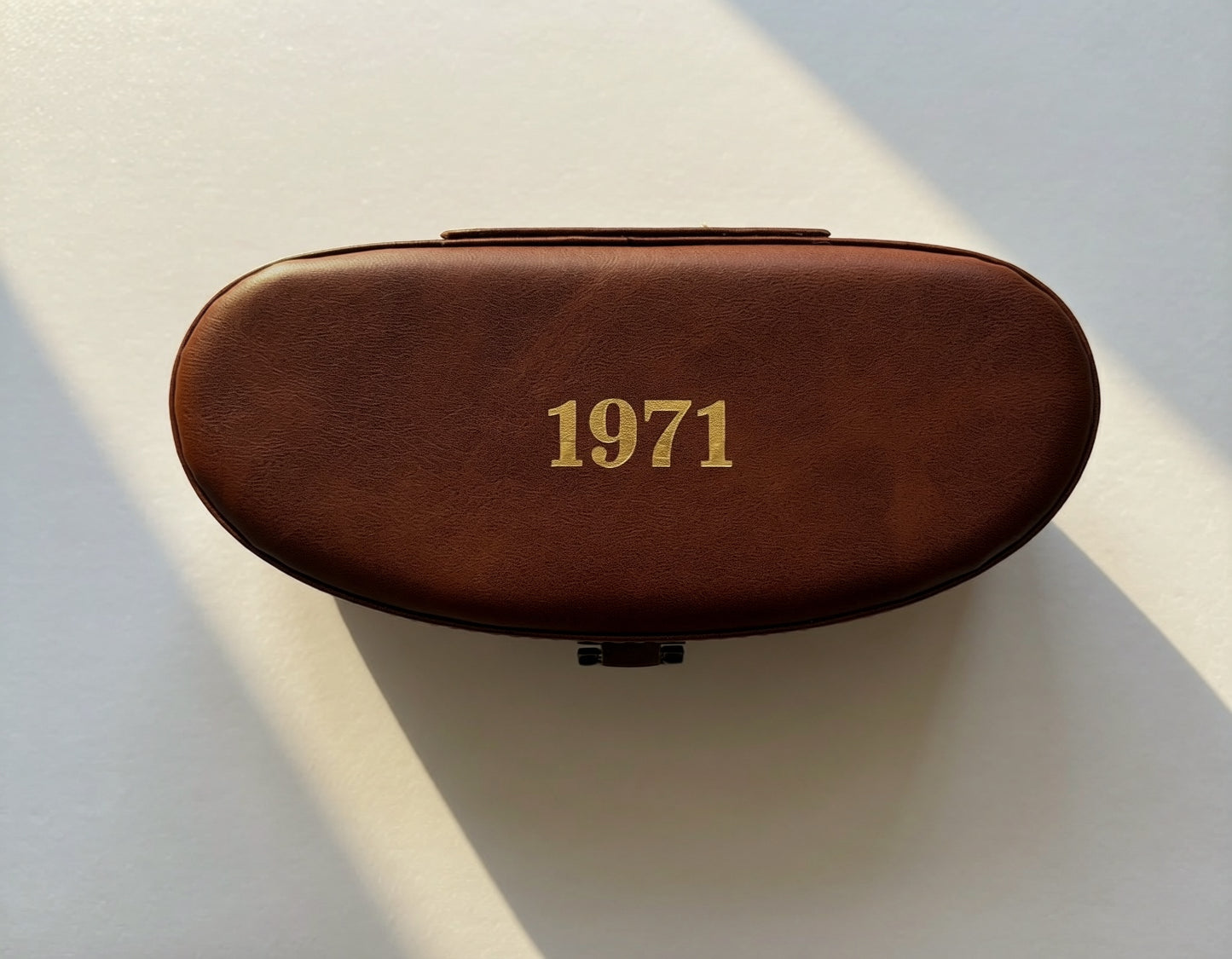 Premium brown leather sunglasses case embossed with 1971 logo, designed for luxury eyewear protection and timeless storage.