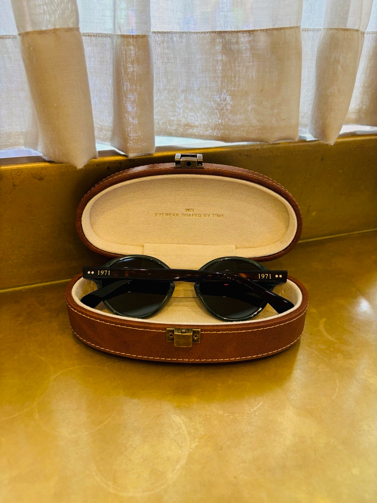 Minimal olive green round frame sunglasses by 1971 Studio inspired by vintage British automotive design.
